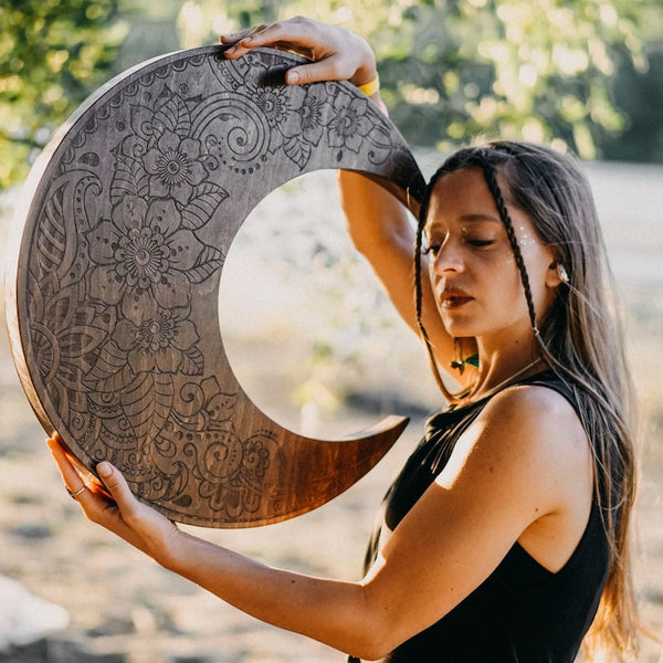 Young woman with long brown hair holding crescent wooden Nazar Crescent Waterfall Disc with floral etching