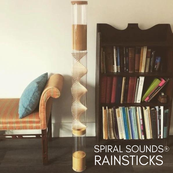 Extra Large Amaranth Spiral Sounds Rainstick in front of an orange couch and small wood bookcase full of books