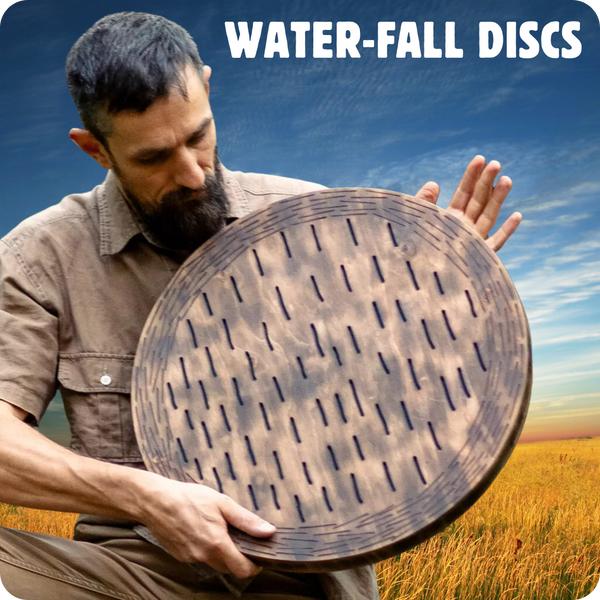 Man with beard siting in grassy field holding Nazar Water-Fall Disc in lap